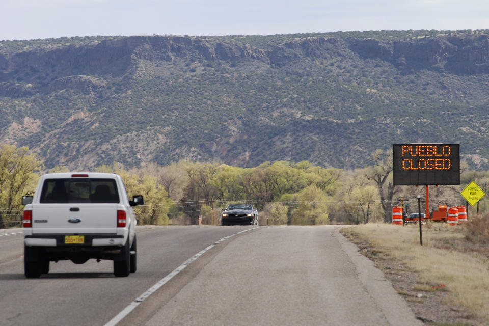 A sign at the Native American community of San Idefonso Pueblo, N.M., urges visitors to stay away as small Indian pueblos throughout the state seek to shield themselves from COVID-19 infection, Thursday, April 23, 2020. San Ildefonso was invited to participate in universal testing by state health officials. The pandemic has raged across the nearby Navajo Nation and Zia and San Felipe pueblos. (AP Photo/Morgan Lee)