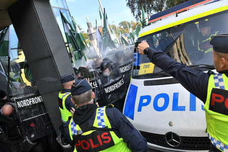 A police officer uses pepper spray on NMR demonstrators as they try to walk along a forbidden street during the Nordic Resistance Movement (NMR) march in central Gothenburg, Sweden September 30, 2017. Fredrik Sandberg/TT News Agency/via REUTERS