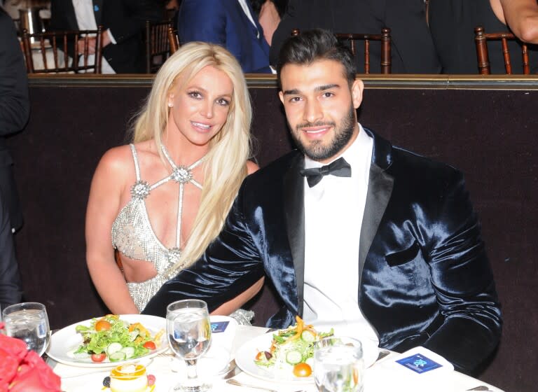 A woman in a silver dress sitting at a dinner table with a man in a blue velvet suit