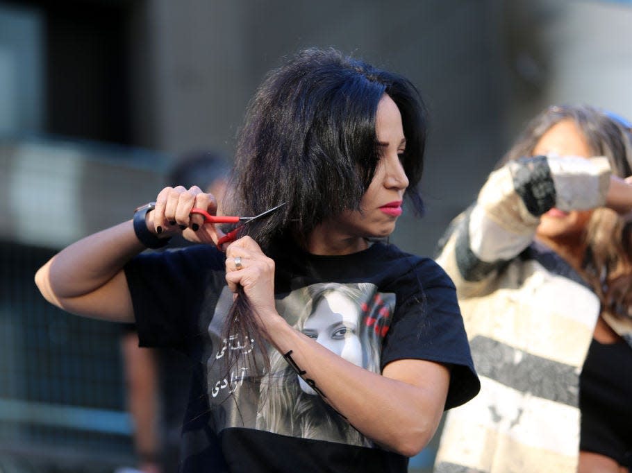 A woman cuts her hair outside Vancouver Art Gallery, during a solidarity protest for Mahsa Amini.