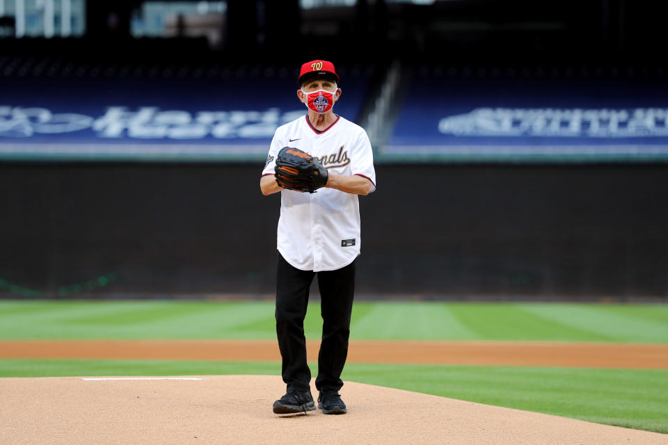 Dr. Anthony Fauci stands on a baseball mound wearing a mask.