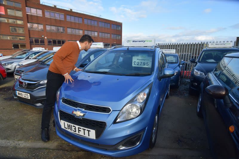 Ameen Sultani looks inside a car as he shows some of the older, cheaper vehicles that have been popular with customers eager to avoid public transport during the coronavirus disease (COVID-19) pandemic, in Hayes