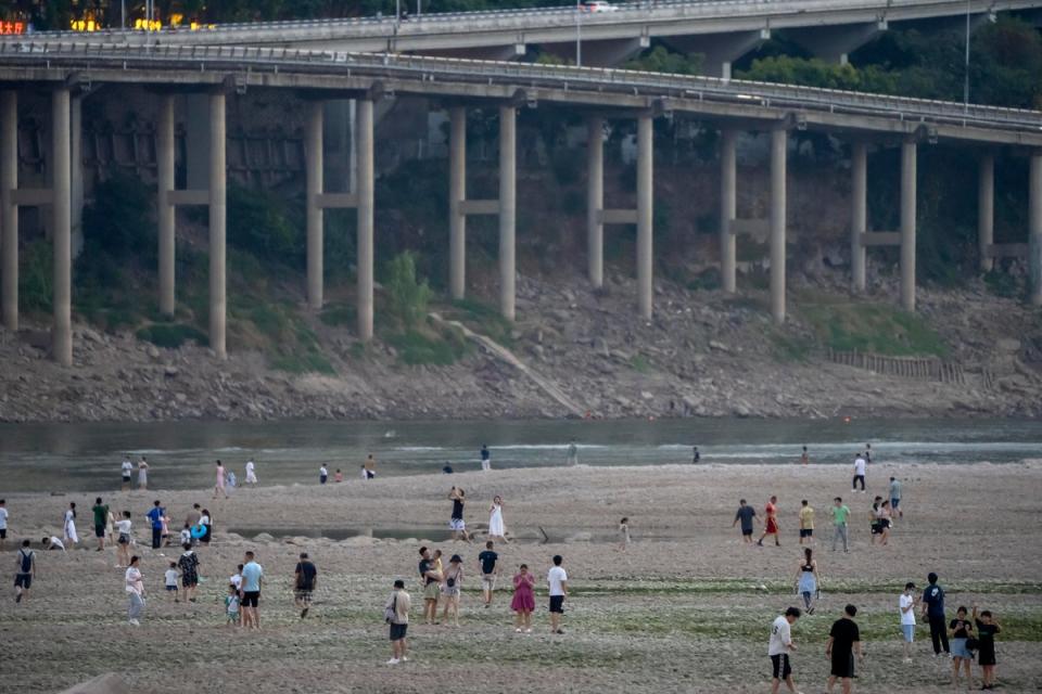 People walk along the dry riverbed of the Jialing River, a tributary of the Yangtze, in Chongqing municipality on 20 August. The very landscape of Chongqing, has been transformed by China’s worst heat wave since modern record-keeping began (AP)