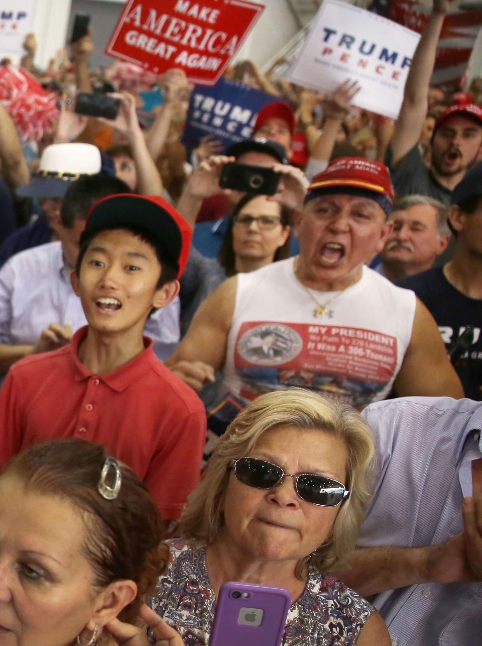 In this file picture from 2017, Cesar Sayoc, far right in red hat, is seen as President Donald Trump speaks during a campaign rally at the AeroMod International hangar at Orlando Melbourne International Airport on February 18, 2017 in Melbourne, Fla. Mr