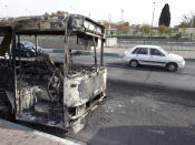 This photo released by the Iranian Students' News Agency, ISNA, shows cars drive past a scorched public bus that remained on the street after protests that followed authorities' decision to raise gasoline prices, in Tehran, Iran, Sunday, Nov. 17, 2019. Ayatollah Ali Khamenei, Iran's supreme leader, on Sunday backed the government's decision to raise gasoline prices and called angry protesters who have been setting fire to public property over the hike "thugs," signaling a potential crackdown on the demonstrations. (Morteza Zangane/ISNA via AP)