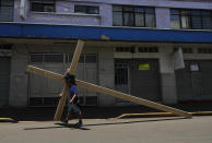 Alejandro Hernandez carries a cross to commemorate Jesus' crucifixion, through the popular neighborhood of Iztapalapa, in Mexico City, Friday, April 10, 2020, where police set up a barricade to keep faithful from gathering for the annual Way of the Cross reenactment. Christians are marking Good Friday in a world locked down by the COVID-19 pandemic, unable to attend solemn church services or religious processions as in past years. (AP Photo/Marco Ugarte)