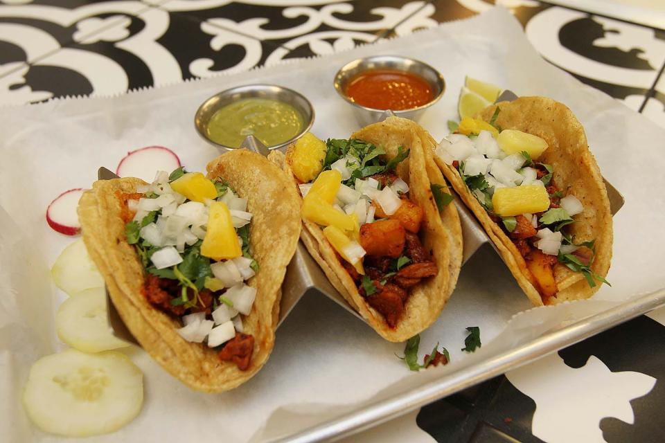 Al pastor street tacos, made with marinated pork with grilled pineapple, are served with homemade guacamole and house sauce on the side at Amigos Taqueria in Stow.