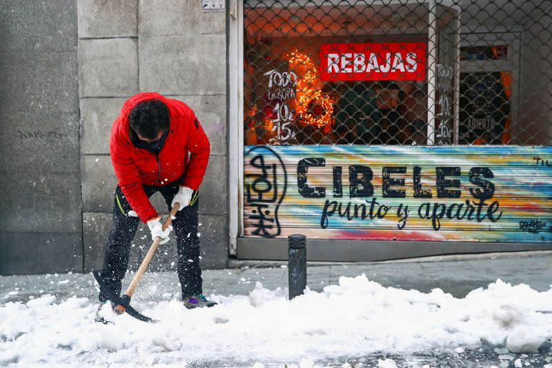 Man uses an axe to break ice, in Madrid