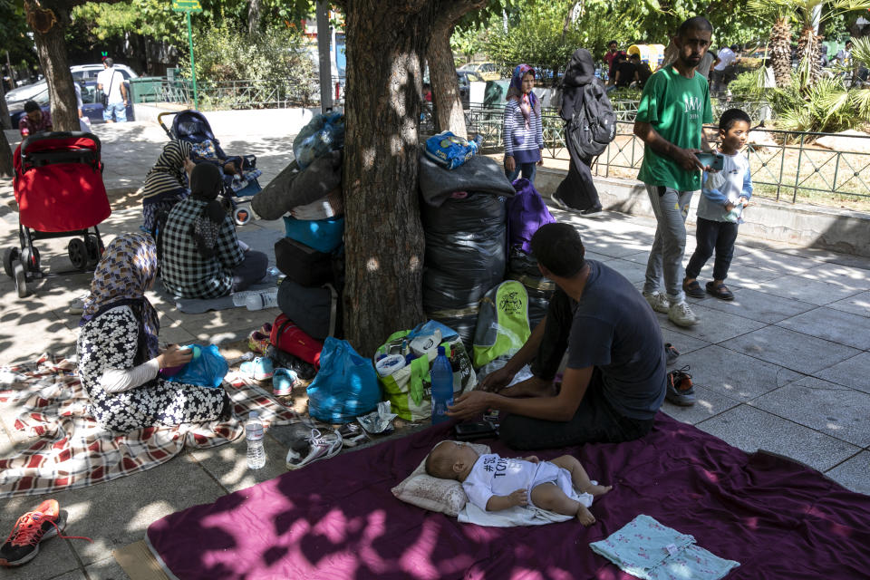 Migrants with their belongings, sit at central Victoria square in Athens, on Wednesday, Sep. 2, 2020. Greece's Shipping Minister says Greek authorities have managed to prevent the arrival of thousands of migrants seeking to enter Greece clandestinely by sea despite a recent lack of cooperation from the Turkish coast guard. (AP Photo/Yorgos Karahalis)
