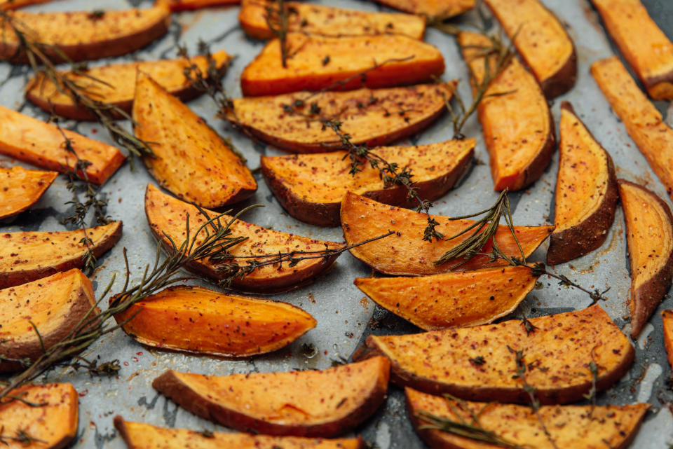 tray of oven baked sweet potato chips in closeup. Baked with paprika, rosemary and salt. Homemade cooked sweet potatoes with spices and herbs on oven-tray.