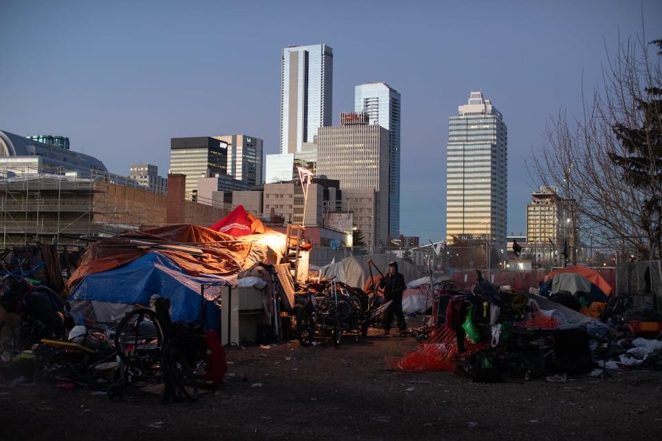 A man prepares to move his belongings as police and cleanup crews prepare to tear down homeless encampments in Edmonton on December 29, 2023. (Jason Franson/The Canadian Press - image credit)