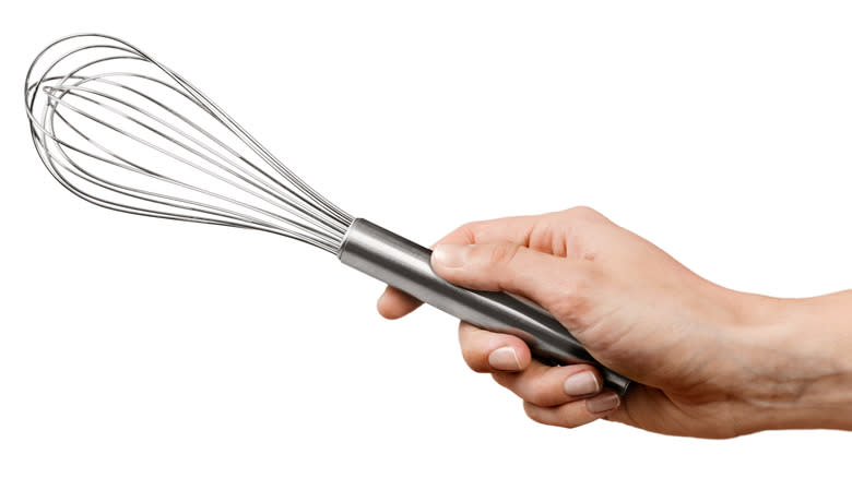 Person holding a hand whisk