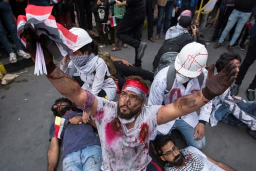 Iraqi actors hand out flags labelled with the names of towns where some of the nearly 430 people killed in the protests came from