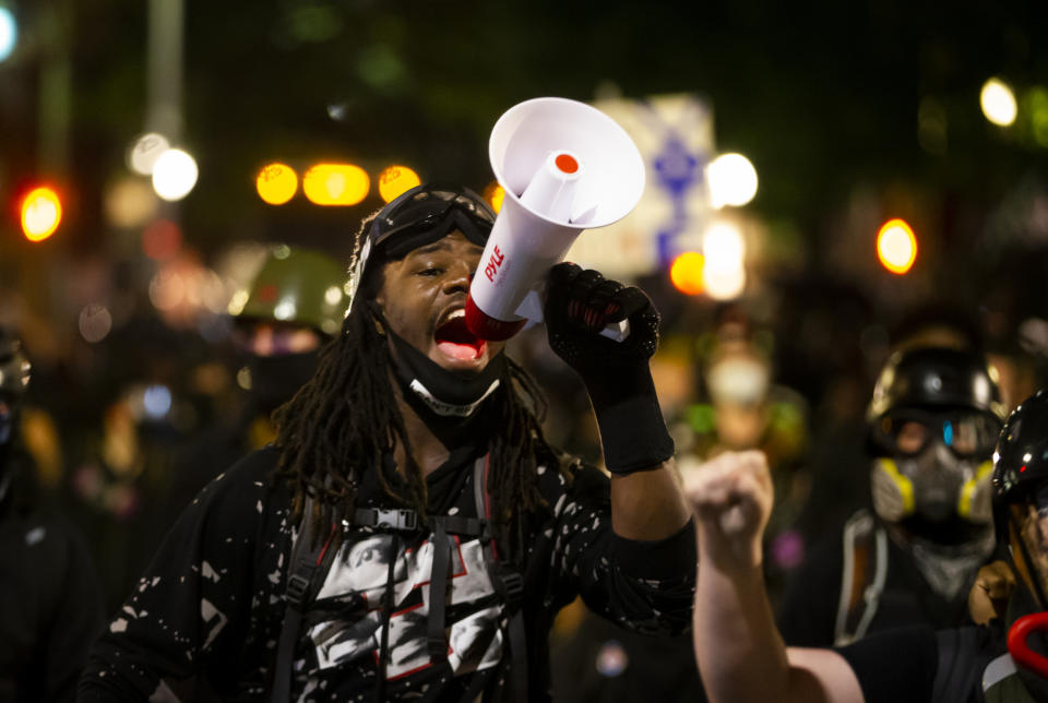 A protester uses a megaphone during a demonstration in Portland, Ore., on Tuesday, Aug. 25, 2020. Officials say protesters in Portland smashed windows at City Hall in a demonstration that started Tuesday night and stretched into Wednesday morning. (Dave Killen/The Oregonian via AP)