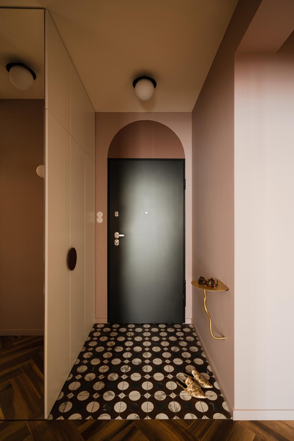 Yana designed a whimsical foyer with a series of rounded elements, from the arched doorway and polka-dot tile floors to the spherical light fixture and circular coat closet handles.