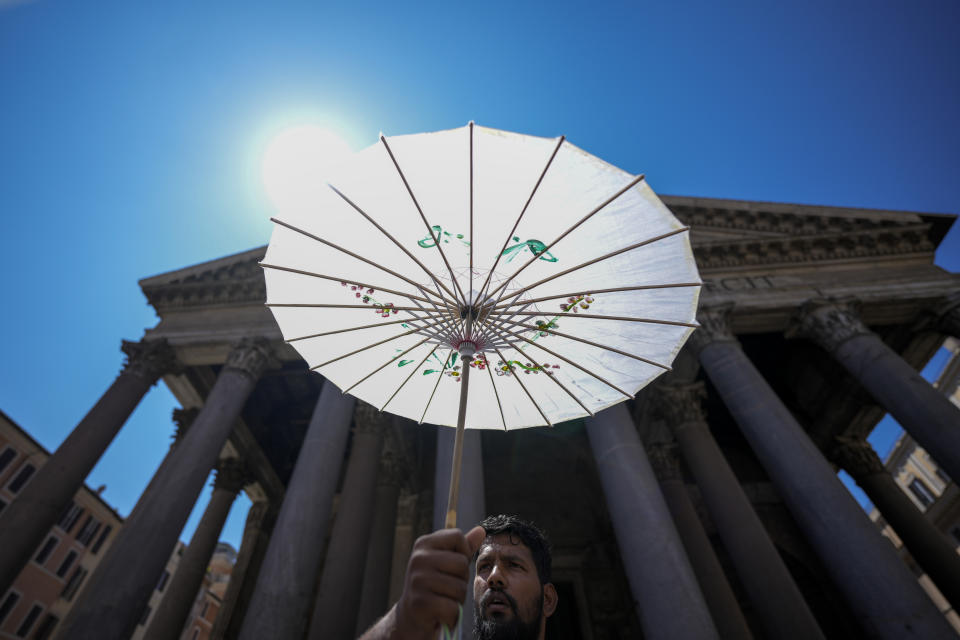 A man shields from the sun with a paper umbrella in front of Rome's Pantheon during a heat wave, Thursday, July 11, 2024. Italian authorities declared a red weather alert in seven cities on Thursday, mostly in the central parts of the country but also the capital Rome and Trieste in the northeast, near the border with Slovenia and Croatia. (AP Photo/Andrew Medichini)