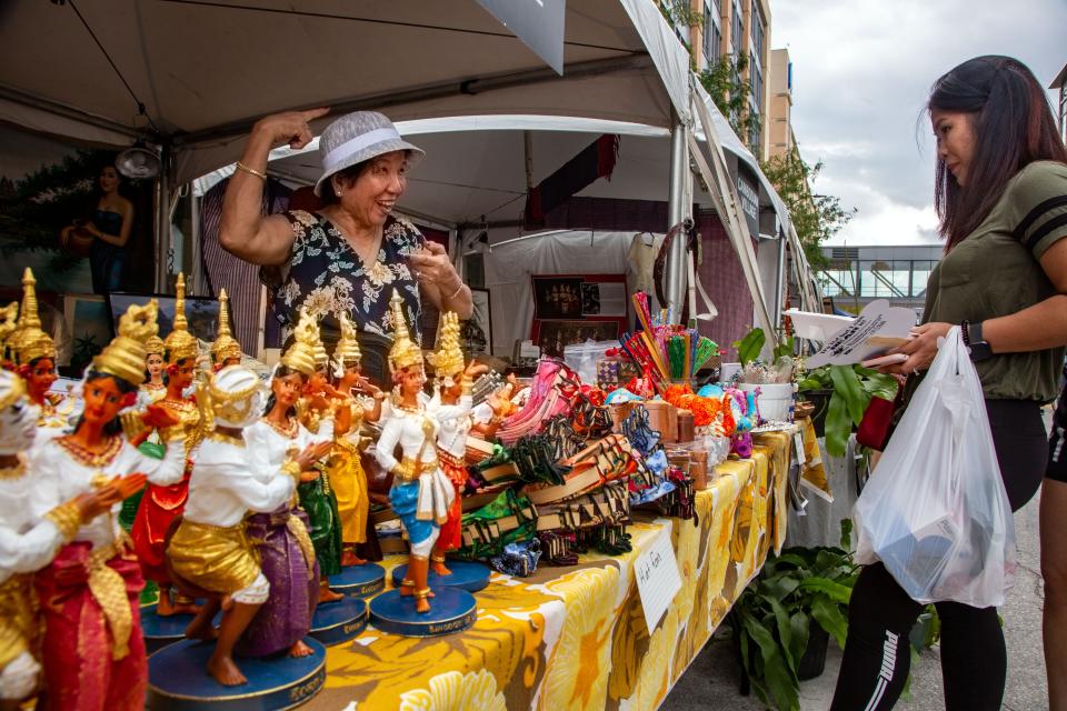 Siemy Poam sells goods to Dah Trinh at the Cambodian Village during CelebrAsian at the Western Gateway Park in Des Moines,  Friday, Oct. 1, 2021.