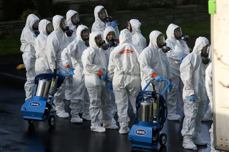Members of a Servpro cleanup crew wearing hazardous material suits prepare to enter Life Care Center of Kirkland, the Seattle-area nursing home at the epicenter of one of the biggest coronavirus outbreaks in the United States, in Kirkland