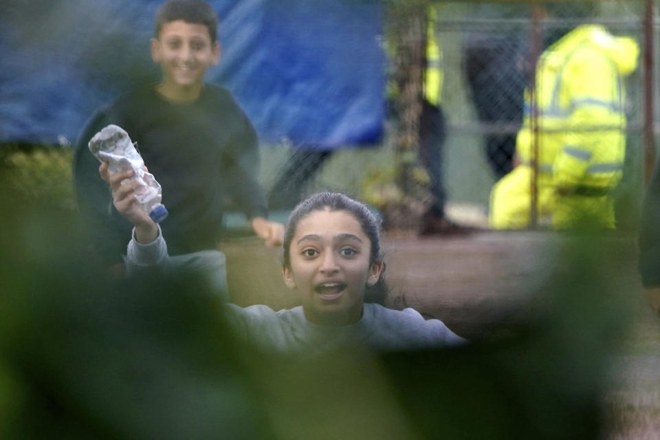 Una niña corre hacia una valla llevando un mensaje en una botella dentro de un centro de retención de inmigrantes a corto plazo de Manston, en Thanet, Inglaterra, el miércoles 2 de noviembre de 2022. (Gareth Fuller/PA vía AP)