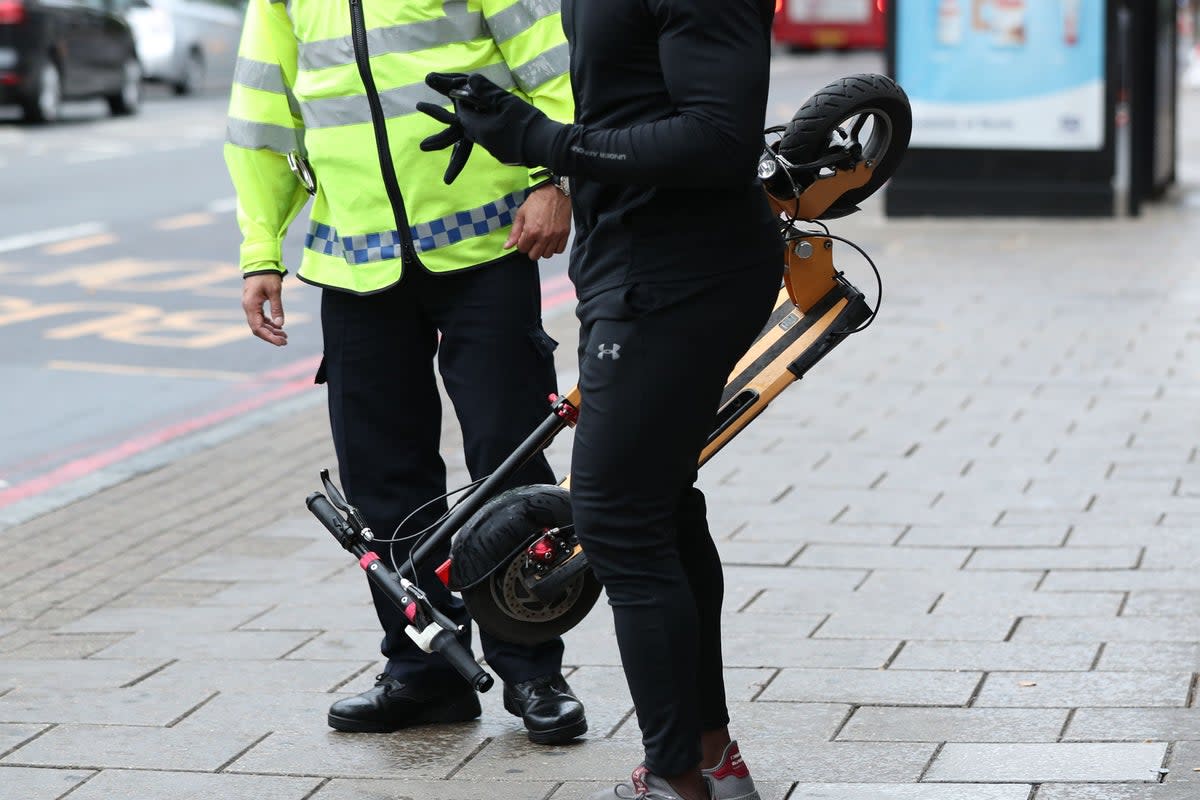 An e-scooter rider is stopped by a police officer in Islington (PA Archive)