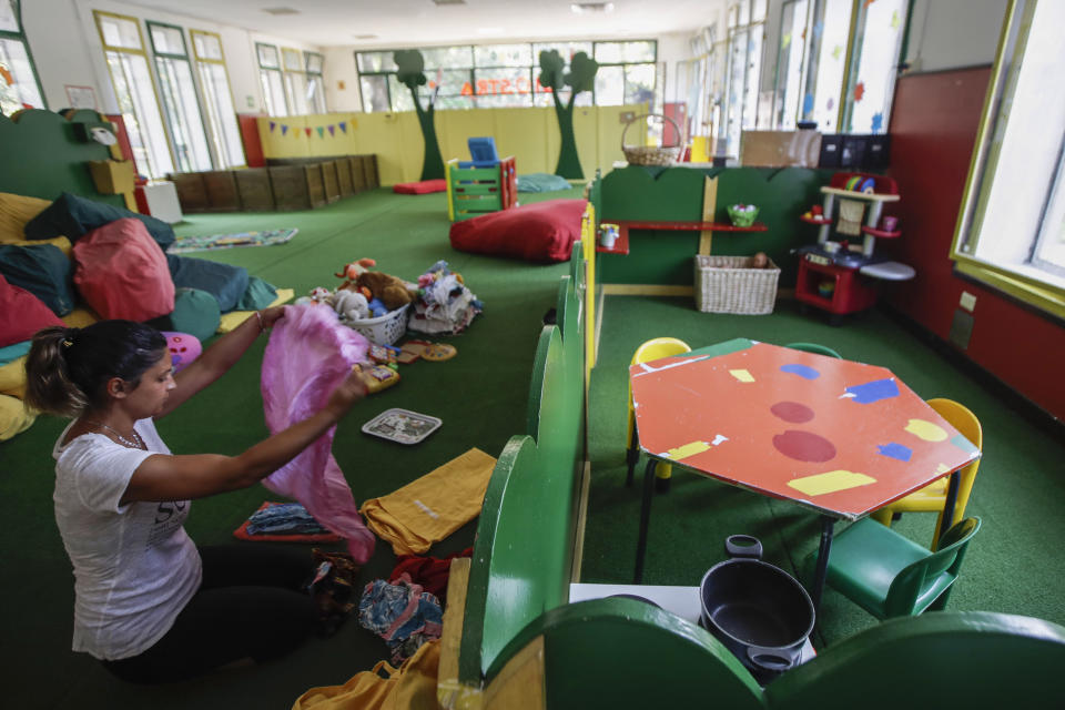 A worker tidies up the playroom in the 'La Giostra Nel Parco' (Merry go around in the park) nursery school in Milan, northern Italy, Thursday, Aug. 27, 2020, ahead of reopening. Despite a spike in coronavirus infections, authorities in Europe are determined to send children back to school. Italy, Europe’s first virus hot spot, is hiring 40,000 more temporary teachers and ordering extra desks, but some won’t be ready until October. (AP Photo/Luca Bruno)