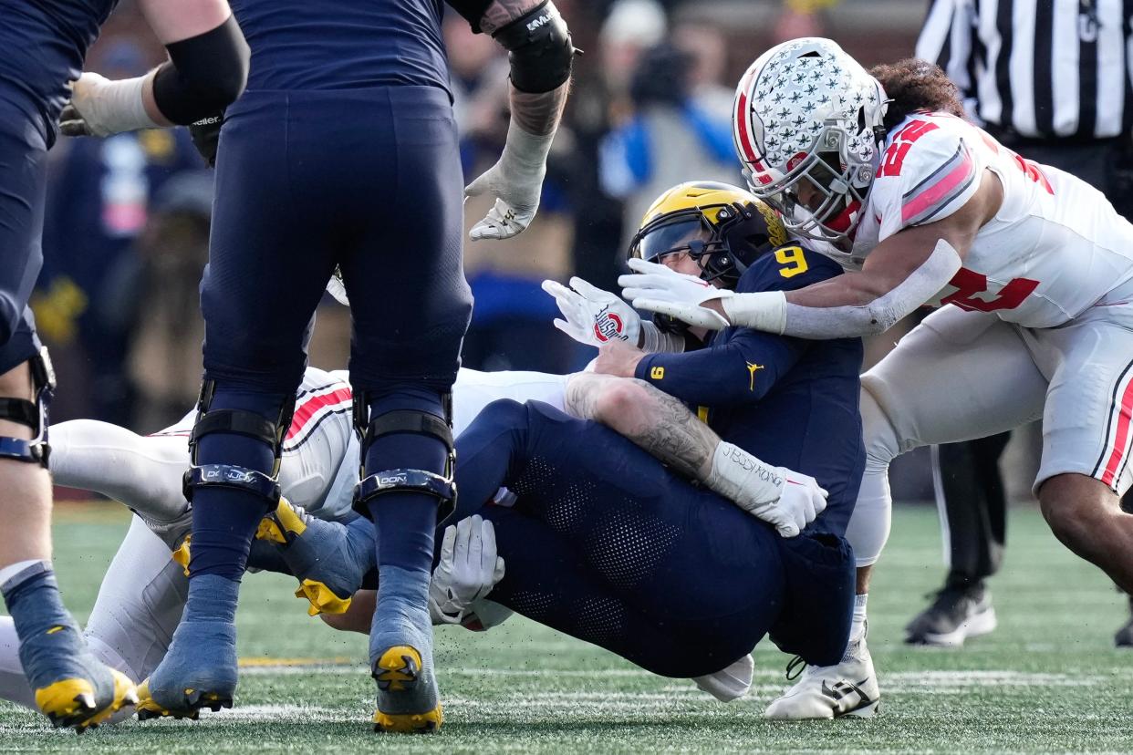 Ohio State defensive end and linebacker Steele Chambers (right) sack Michigan quarterback J.J. McCarthy.