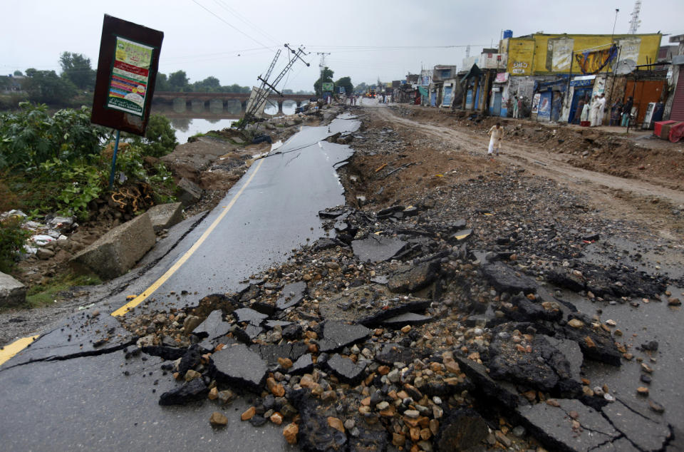 A man walks alongside a damaged portion of a road caused by a powerful earthquake n Jatla near Mirpur, in northeast Pakistan, Wednesday, Sept. 25, 2019. Mourners were burying their dear ones in Pakistan-held Kashmir where a powerful earthquake struck a day before. (AP Photo/Anjum Naveed)