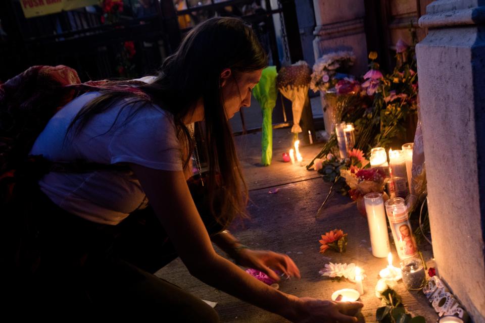 A person lays a candle outside Ned Pepper's Bar during a vigil for the victims of  a mass shooting in the Oregon District of Dayton, Ohio, on Sunday, Aug. 4, 2019. 