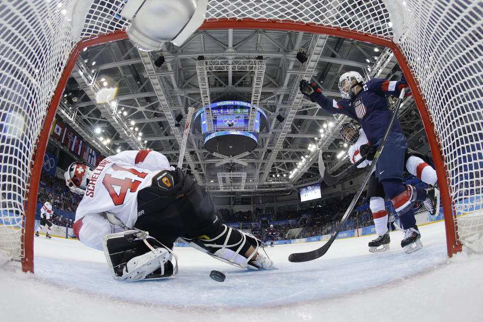 Meghan Duggan of the Untied States celebrates Monique Lamoureux's goal as the puck slides under Goalkeeper Florence Schelling of Switzerland during the second period of the 2014 Winter Olympics women's ice hockey game at Shayba Arena, Monday, Feb. 10, 2014, in Sochi, Russia. USA defeated Switzerland 9-0.