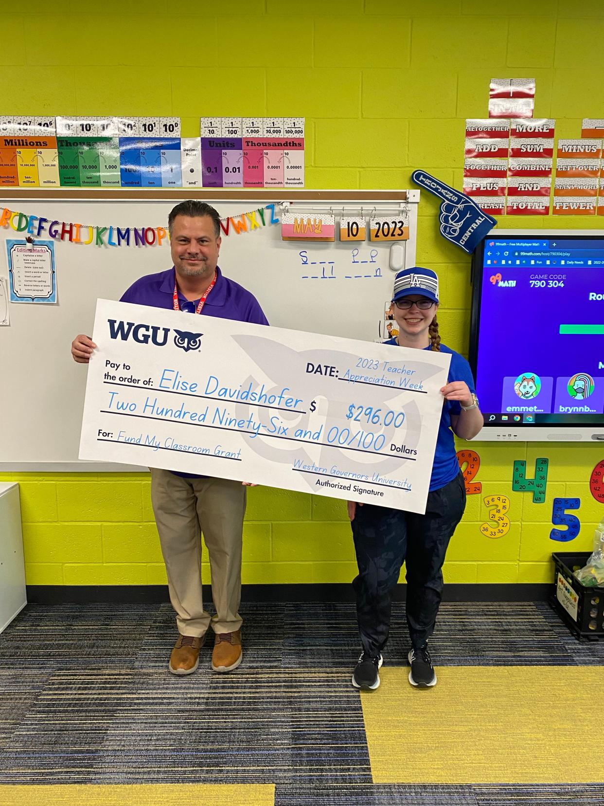 Elise Davidshofer, a fourth-grade teacher at Central Intermediate School in Washington (right) receives a $296 grant check from Western Governors University Strategic Partnerships Manager Dan Winkler.