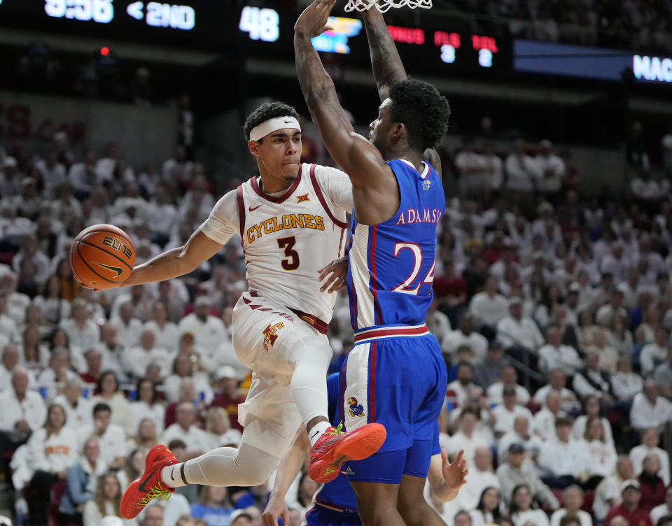 Iowa State guard Tamin Lipsey (3) leaps to pass the ball under the basket behind Kansas forward K.J. Adams Jr. (24) during the second half of an NCAA college basketball game, Saturday, Jan. 27, 2024, in Ames, Iowa. Iowa State won 79-75. (AP Photo/Matthew Putney)