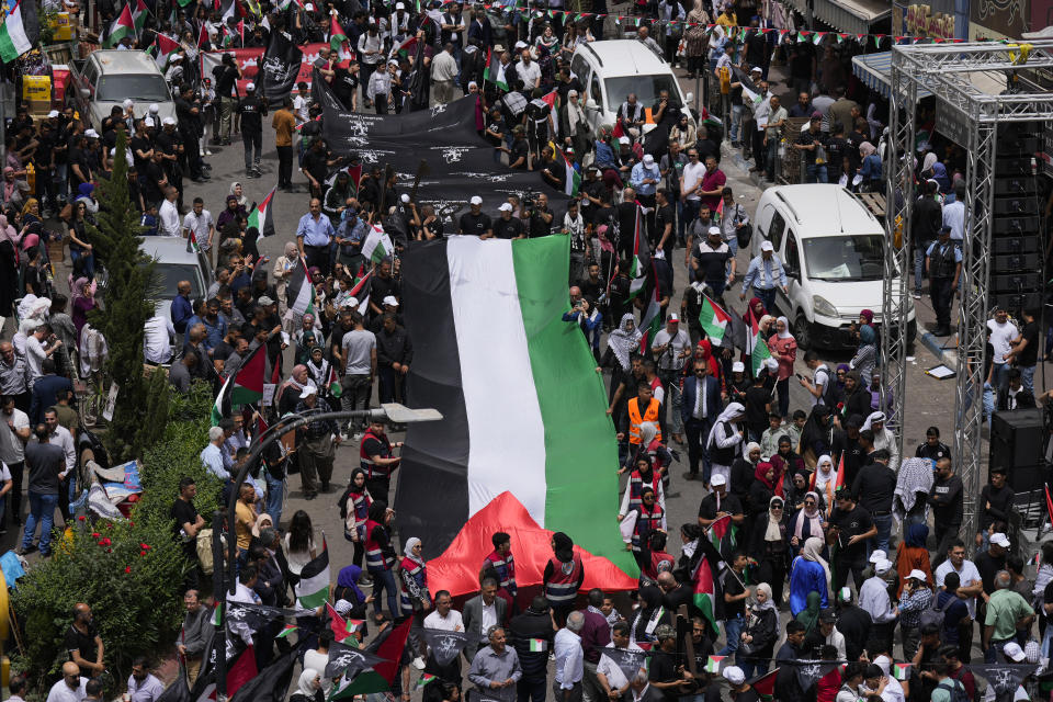 Palestinians carry a large national flag during a rally marking the 74h anniversary of what the Palestinians call the "Nakba," or "catastrophe" referring to their uprooting in the war over Israel's 1948 creation, in the West Bank city of Ramallah, Sunday, May 15, 2022. (AP Photo/Majdi Mohammed)