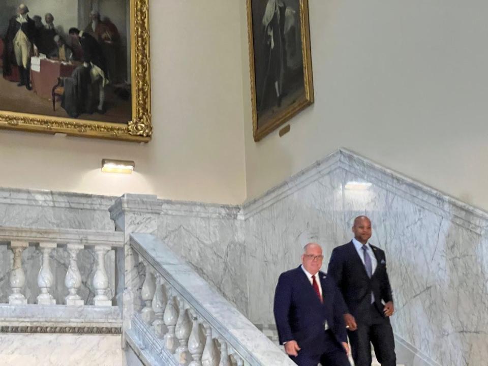 Republican Governor Larry Hogan, left, and Governor-elect Wes Moore, right, walk down the stairs at the State House in Annapolis, Maryland on Nov. 10, 2022. Above them, at left, is a painting of General George Washington resigning his commission of the Continental Army, which Hogan called the "first peaceful transfer of power."