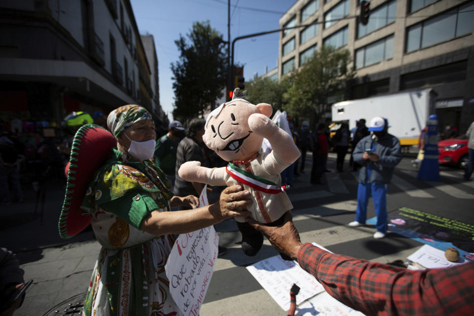 A supporter of Mexico's President Andres Manuel Lopez Obrador holds a doll in his likeness during a demonstration outside of the Supreme Court in Mexico City, Thursday, Oct. 1, 2020. The court is scheduled to decide whether the president's proposal, to hold a popular vote on whether or not to pursue former presidents on corruption charges, stands up to scrutiny. (AP Photo/Fernando Llano)