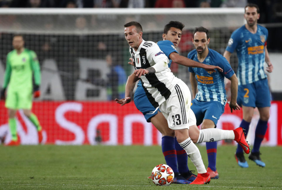 Juventus' Federico Bernardeschi, left, drives the ball past Atletico's Rodrigo Hernandez during the Champions League round of 16, 2nd leg, soccer match between Juventus and Atletico Madrid at the Allianz stadium in Turin, Italy, Tuesday, March 12, 2019. (AP Photo/Antonio Calanni)