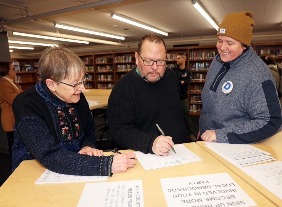 Caucus Secretary Susan Wickham, left, Caucus Chair Kevin Marken, and Executive Director of Polk County Democrats Kira Barker review documents as Democrats brave sub-zero weather to gather in person on Iowa Caucus night Monday at the East High School library in Des Moines.