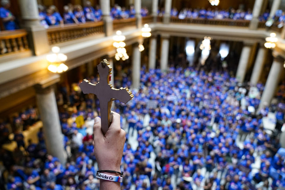 Luke Howard, of Avon, Ind., holds a crucifix aloft as anti-abortion supporters rally as the Indiana Senate Rules Committee met a Republican proposal to ban nearly all abortions in the state during a hearing at the Statehouse in Indianapolis, Tuesday, July 26, 2022. (AP Photo/Michael Conroy)