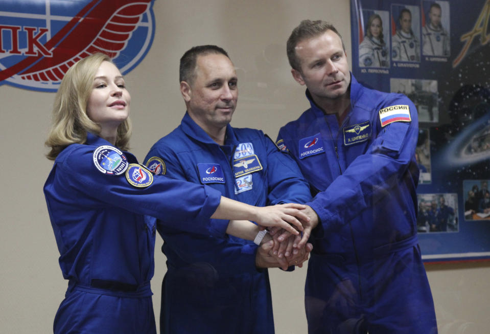 In this handout photo released by Roscosmos, actress Yulia Peresild, left, director Klim Shipenko, right, and cosmonaut Anton Shkaplerov, members of the prime crew of Soyuz MS-19 spaceship pose after a news conference at the Russian launch facility in the Baikonur Cosmodrome, Kazakhstan, Monday, Oct. 4, 2021. In a historic first, Russia is set to launch an actress and a film director to space to make a feature film in orbit. Actress Yulia Peresild and director Klim Shipenko are set to blast off Tuesday for the International Space Station in a Russian Soyuz spacecraft together with Anton Shkaplerov, a veteran of three space missions.(Roscosmos Space Agency via AP)