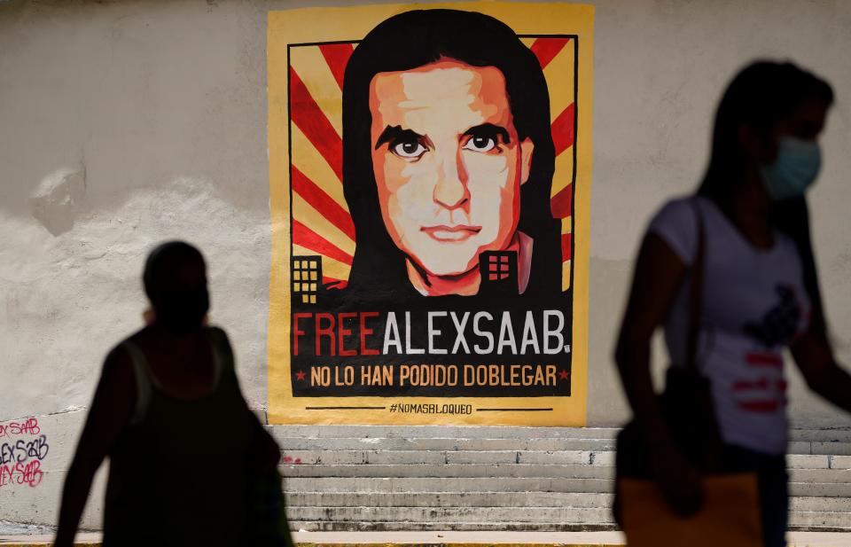 Pedestrians walk near a poster asking for the freedom of Colombian businessman and Venezuelan special envoy Alex Saab, in Caracas, Venezuela, Sept. 9, 2021.