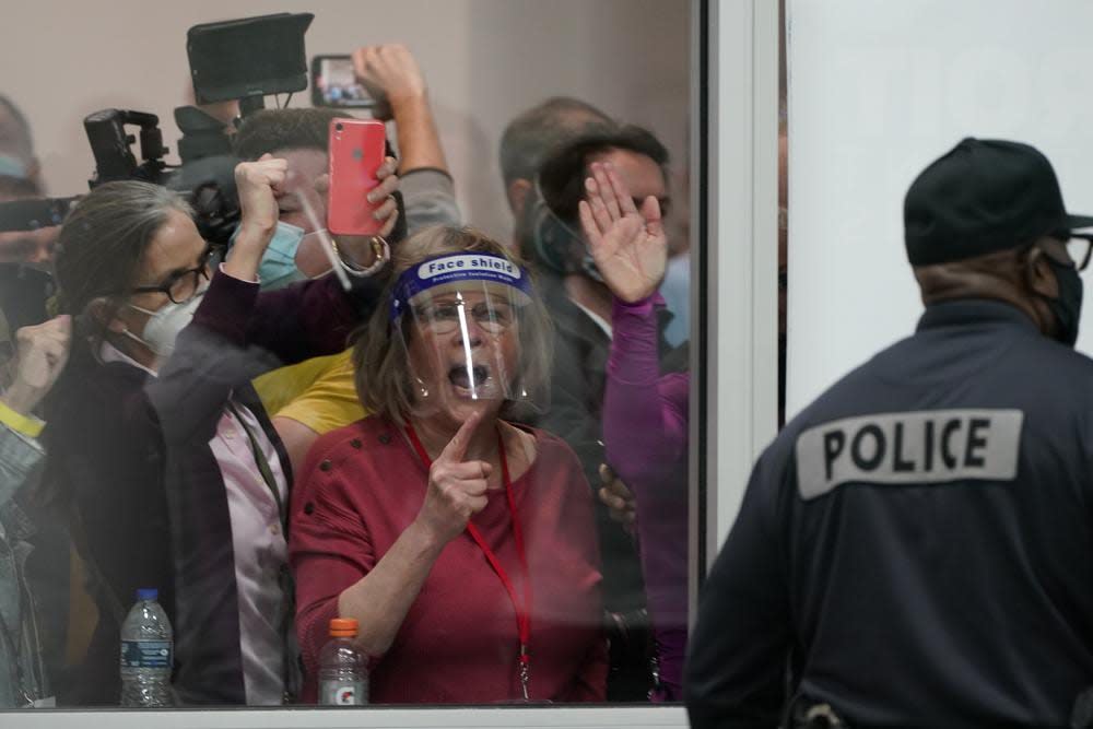 In this Wednesday, Nov. 4, 2020, file photo, election challengers yell as they look through the windows of the central counting board as police were helping to keep additional challengers from entering due to overcrowding, in Detroit. There is no shortage of job openings for election officials in Michigan. And Pennsylvania. And Wisconsin. After facing waves of threats and intimidation during the 2020 election and its aftermath, county officials who run elections are quitting or retiring early as the once quiet job has become a minefield because of the baseless claims of fraud pushed by former President Donald Trump and much of the Republican Party. (AP Photo/Carlos Osorio, File)