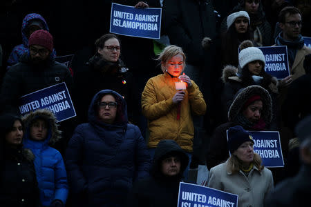 A woman carries a candle at a vigil for victims of the mosque shootings in New Zealand, outside city hall in Toronto, Ontario, Canada March 15, 2019. REUTERS/Chris Helgren