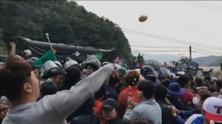 A man throws an object at the convoy of vehicles during a protest opposing the deployment of a Terminal High Altitude Area Defense (THAAD) system in Seongju, South Korea, in this still image taken from a September 7, 2017 social media video. Han Sung/via REUTERS