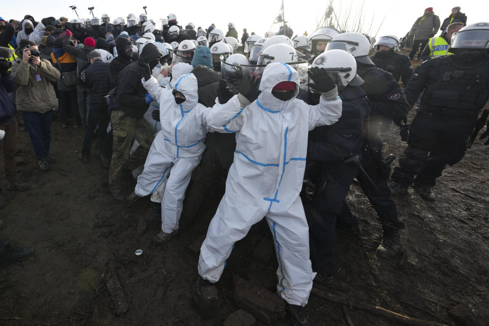 Police officers scuffle with demonstrators at village Luetzerath near Erkelenz, Germany, Tuesday, Jan. 10, 2023. The village of Luetzerath is occupied by climate activists fighting against the demolishing of the village to expand the Garzweiler lignite coal mine near the Dutch border. Poster read: „1,5 degrees celsius means: Luetzerath stays". (AP Photo/Michael Probst)