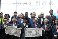 Officials pose with enlarged copies of the new and old 10000 yen banknotes during the "10,000 Yen Bill Handover Ceremony" at Tokyo Stock Exchange Wednesday, July 3, 2024, in Tokyo. New 10000 yen bill featuring a portrait of local figure Shibusawa Eiichi, the "father of Japanese capitalism." From Fukaya City. Nakatsu City is where Yukichi Fukuzawa, a figure of previous 10000 yen bill, was from. (AP Photo/Eugene Hoshiko)