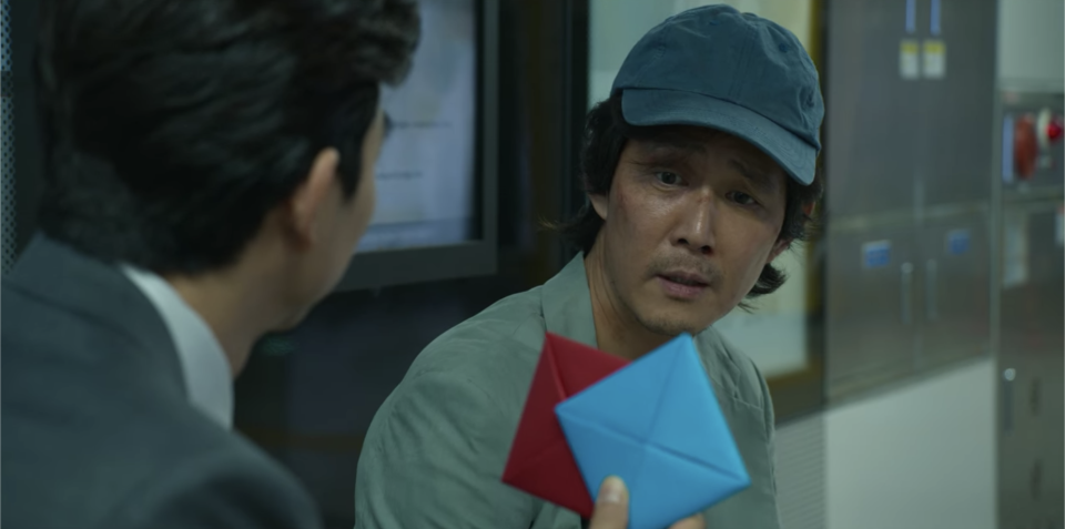 The man holding up two cards in Gi-hun's face