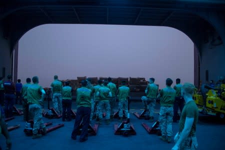 Sailors assigned to the U.S. Navy amphibious assault ship USS Boxer prepare to receive stores off the port-side elevator in the Arabian Sea