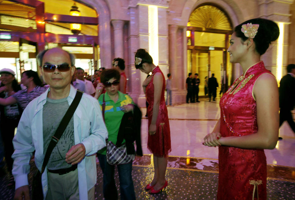 FILE - In this May 15, 2011 file photo, mainland Chinese visitors walk past attendants at the Galaxy Macau in Macau. In the Philippines, a $4 billion casino project will soon rise from reclaimed land on Manila Bay. In South Korea, foreign investors will break ground next year on a clutch of casino resorts offshore. And on the eastern edge of Russia, authorities plan a resort zone aimed at drawing Chinese high-rollers. The projects are part of a casino building boom rolling across Asia, where governments are trying to develop their tourism markets to capture increasingly affluent Asians with a penchant for gambling. (AP Photo/Vincent Yu, File)