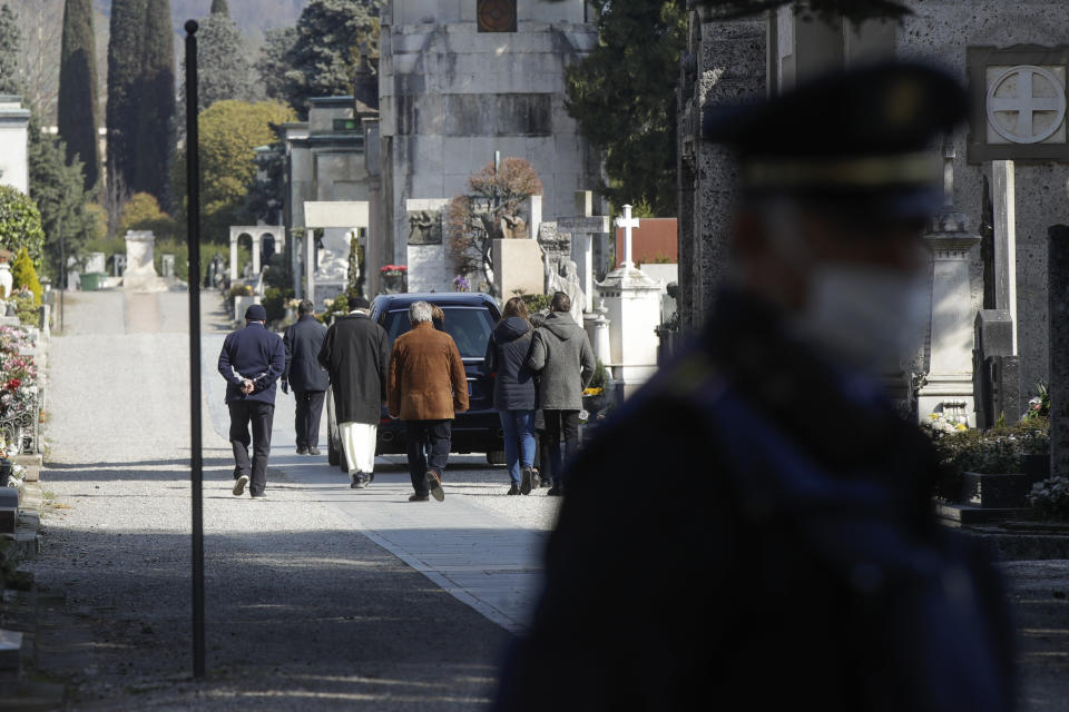 FILE - In this Tuesday, March 17, 2020. filer, relatives walk behind a hearse carrying a coffin inside the Monumentale cemetery, in Bergamo, the heart of the hardest-hit province in Italy’s hardest-hit region of Lombardy, Italy. Italy is seeing a slight stabilizing in its confirmed coronavirus infections two weeks into the world’s most extreme nationwide shutdown, but the virus is taking its silent spread south after having ravaged the health care system in the north. The new coronavirus causes mild or moderate symptoms for most people, but for some, especially older adults and people with existing health problems, it can cause more severe illness or death. (AP Photo/Luca Bruno, File)