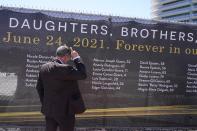 FILE - Pablo Langesfeld looks at the name of his daughter Nicole Langesfeld, Thursday, May 12, 2022, in Surfside, Fla., on a large banner with the names of the 98 killed in the collapse of the Champlain Towers South building. Attorneys for the families who lost relatives or homes in last year’s collapse of a Florida condominium tower that killed 98 people finalized a $1 billion settlement on Friday, May 27, 2022. (AP Photo/Marta Lavandier, File)