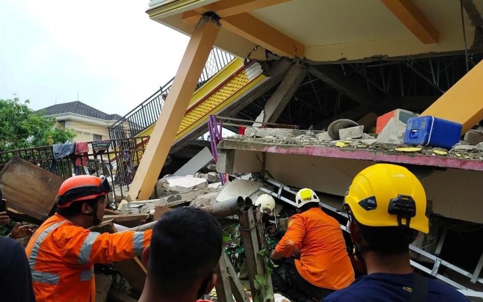 Members of a search and rescue agency team dig through rubble after an earthquake, in Mamuju - Reuters